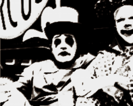 IMAGE IDENTIFICATION. A drawing of a clown, Charlie. The image itself is drawn to mimick the look of an old film photograph, with thick brown black shadows contrasted with brown white highlights. Its also very pixelated.The shadows are too dark to see Charlies, eyes, which are covered now in diamond shaped eye makeup. His mouth is in shadow as well, as the camera cant clearly make out the lipstick hes wearing. His lips are painted so it looks like hes in a perpetual frown. Hes sitting beside another clown, whos also looking at the camera, and looks to be happier. His face is cut off by the end of the photograph. END ID